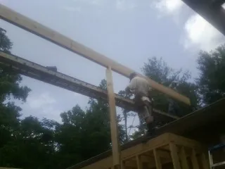 Carpenter setting a ridge beam over a new addition frame — Ice Dam Removal by Roofing Brothers in Big Prairie