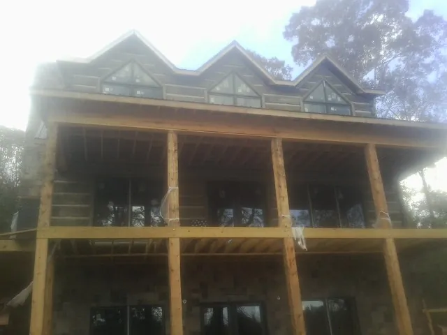 Dormers and porch framing on a large log home under construction — Roof Coating work by our crew in Big Prairie