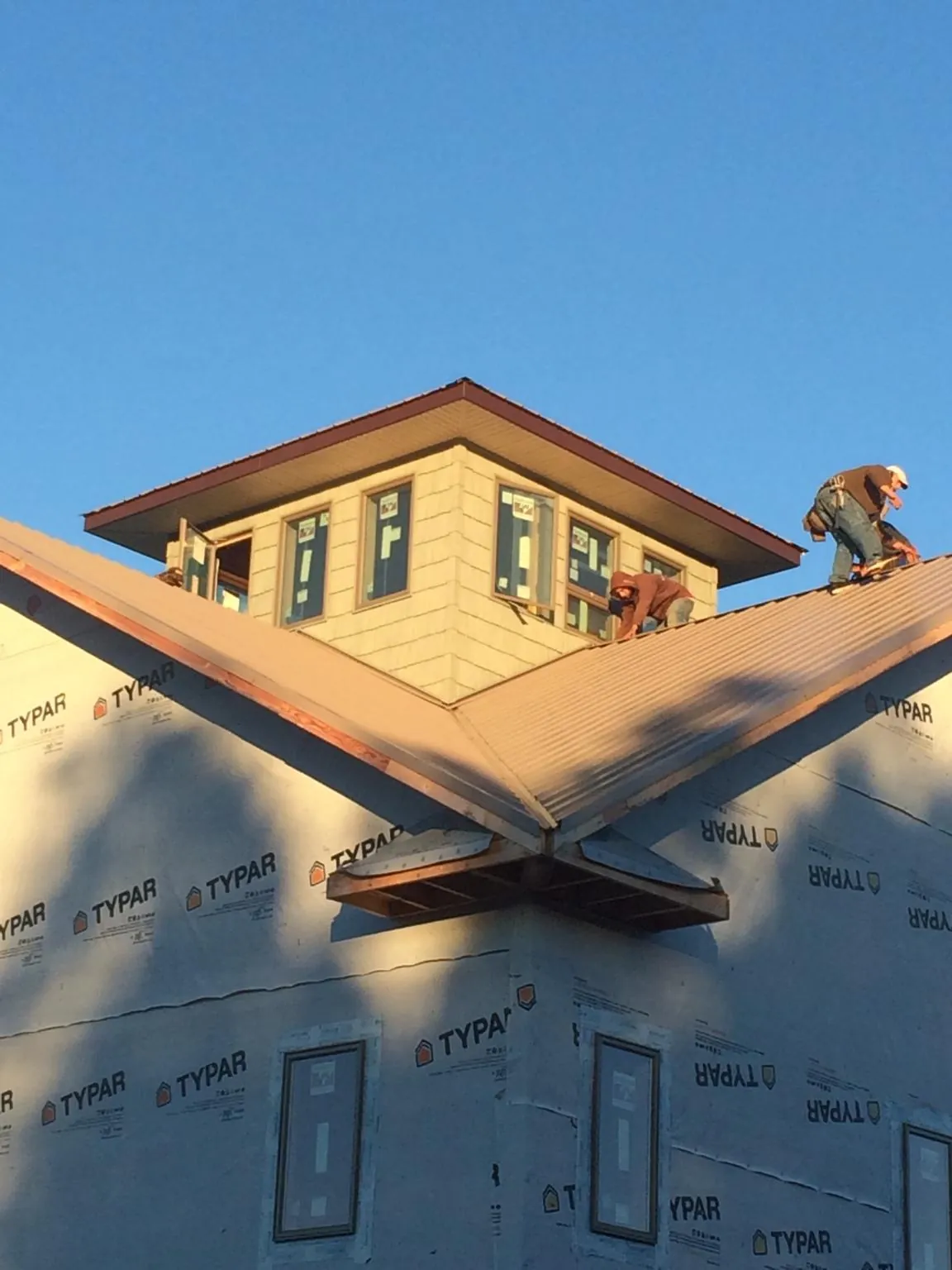 Roofers working around a rooftop cupola on a new metal roof at sunset — Roof Waterproofing in Big Prairie by Roofing Brothers